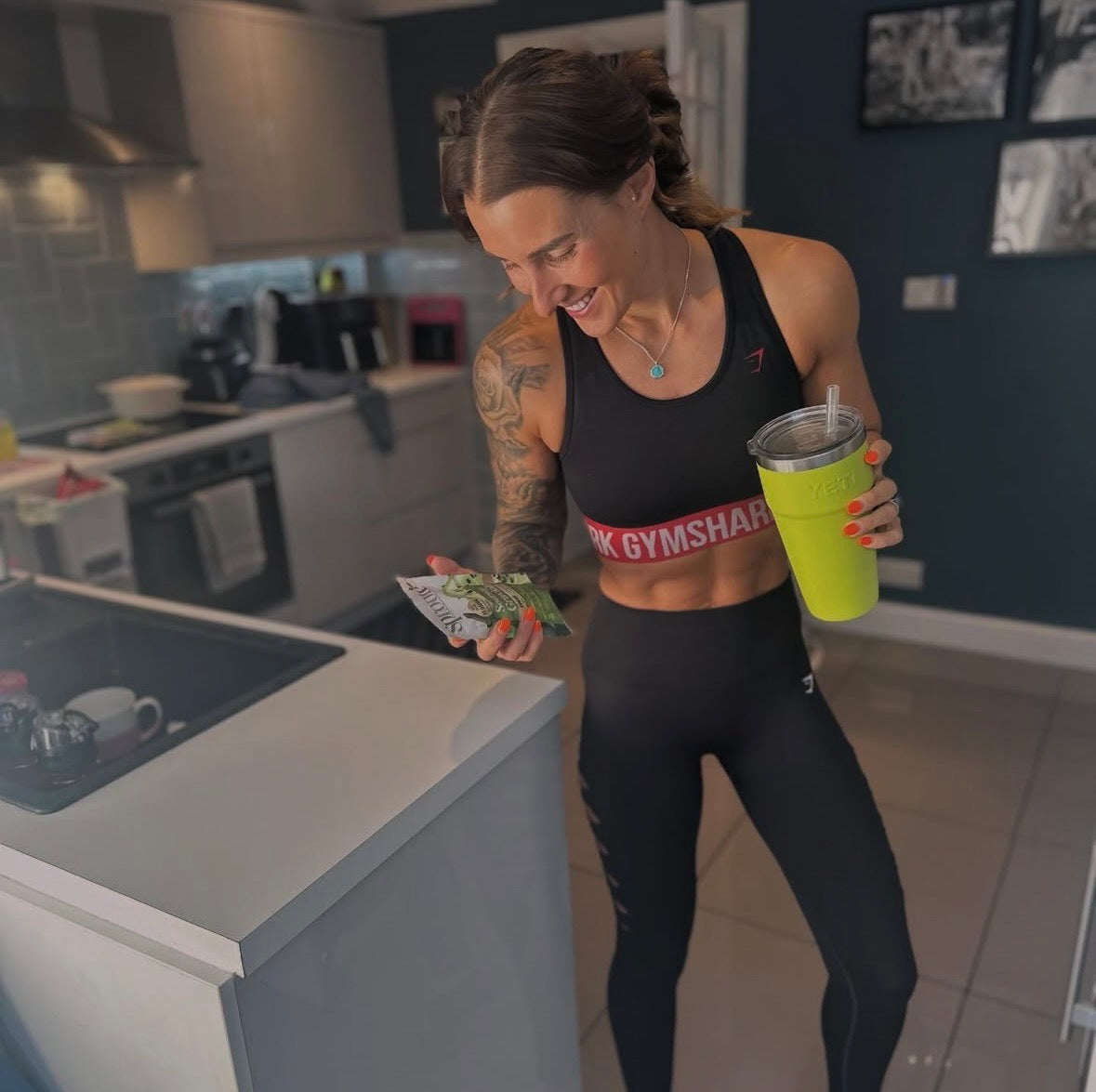 Sproote customer in workout wear holding a Sproote pouch in her kitchen
